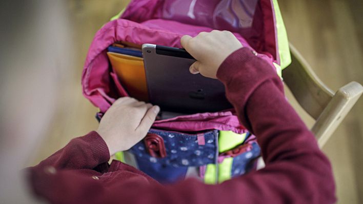 Ein Maedchen packt ein Tablet in ihren Schulranzen (Bild: imago/Janine Schmitz)