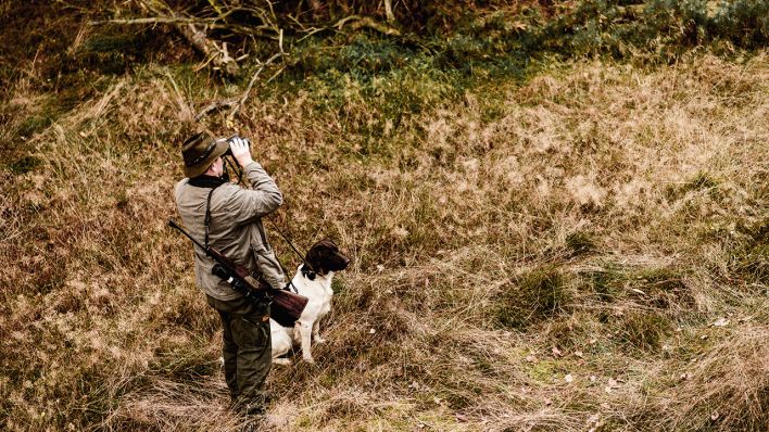 Symbolbild: Ein Jäger mit Hund hält in Brandenburg mit seinem Fernglas Ausschau. (Quelle: dpa/Schlesinger)