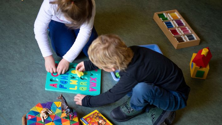 Ein Junge und ein Mädchen spielen in einem Kindergarten auf dem Boden (Quelle: ZB/Monika Skolimowska)