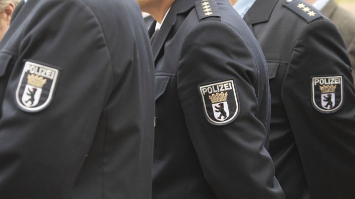 Drei Männer haben Jackets an, auf denen sich Abzeichen der Berliner Polizei befinden (Quelle: DPA/Paul Zinken)