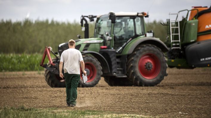 Ein junger Landwirt läuft zu einem Traktor. (Quelle: imago images/Florian Gaertner)