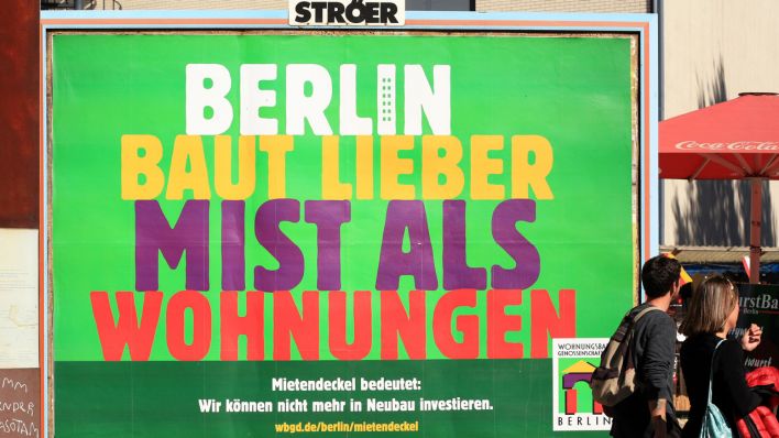 Fußgänger gehen im Bezirk Mitte an einem Großplakat mit der Aufschrift "Berlin baut lieber Mist als Wohnungen " vorbei.