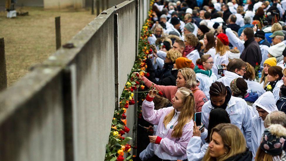 Besucher stecken Blumen in die Mauerüberreste an der Bernauer Straße (Quelle: dpa/Schreiber)