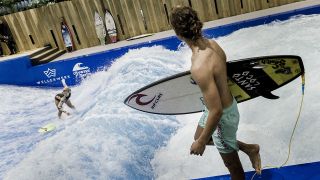 Eine Surferin springt auf einer künstlichen Surfwelle in der Indoor-Surfhalle Wellenwerk (Quelle: DPA/Carsten Knoll)