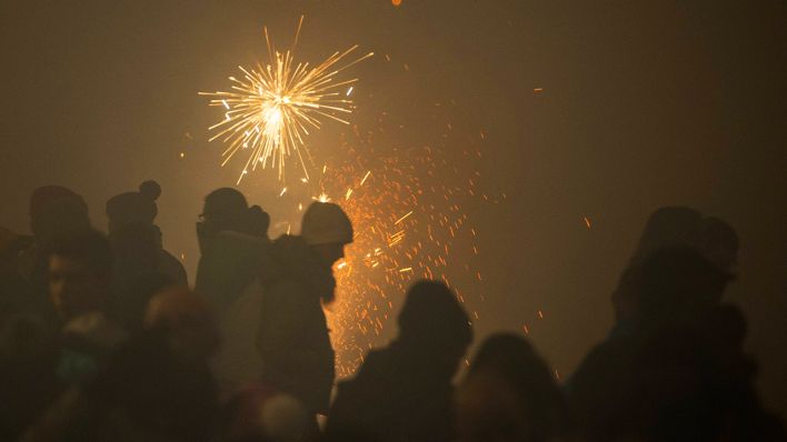 Symbolbild: Menschen stehen bei einem Silvesterfeuerwerk im Nebel und sind im Dunst kaum zu erkennen. (Quelle: imago images/R. Michael)