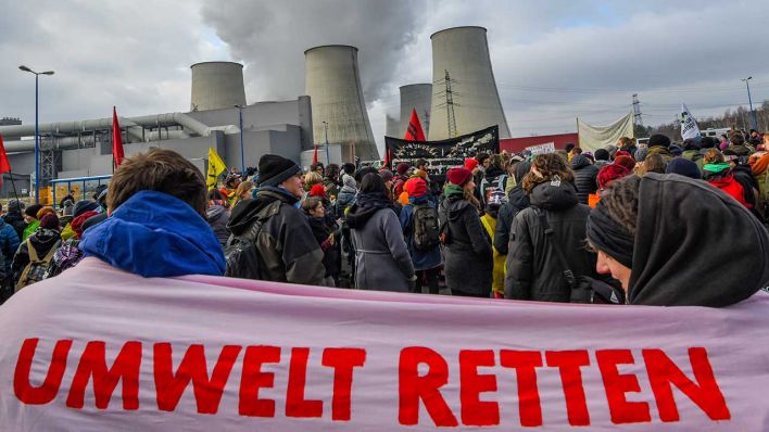 Umweltschutzaktivisten halten ein Banner mit der Aufschrift «Umwelt retten» vor den dampfenden Kühltürmen des Braunkohlekraftwerkes Jänschwalde der Lausitzer Energie Bergbau AG (LEAG). (Bild: dpa/Pleul)