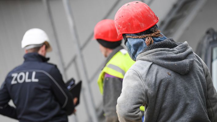 Ein Beamter des Zoll kontrolliert Bauarbeiter während eines Einsatzes auf einer Großbaustelle (Quelle: dpa/Arne Dedert)