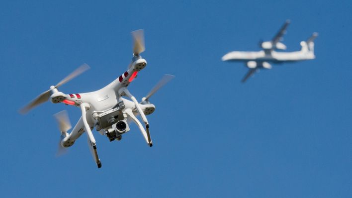 Symbolbild: Eine private Drohne fliegt in in weiter Entfernung von einem Flugzeug, das im Anflug auf den Flughafen Düsseldorf ist. (Quelle: dpa/Julian Stratenschulte9