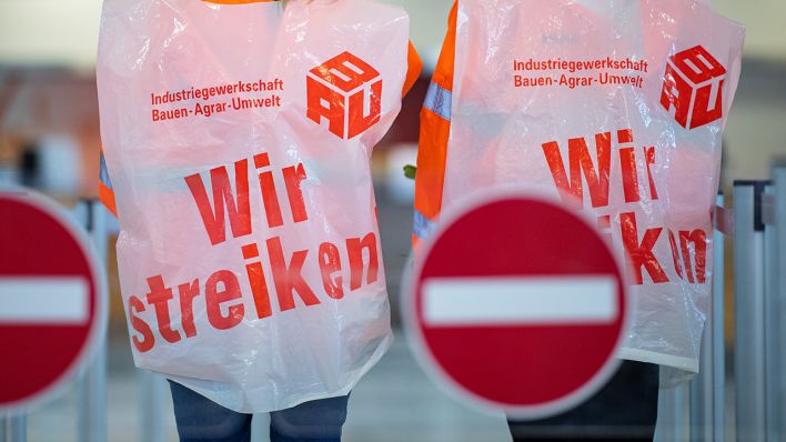 Zwei Mitarbeiter von Reinigungsfirmen tragen Westen mit der Aufschrift "Wir streiken" (Quelle: dpa/Kirchner).