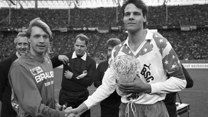 Die beiden Mannschaftskapitäne Olaf Seier (Union) und Dirk Greiser (Hertha) geben sich beim Wiedervereinigungsspiel am 27. Januar 1990 die Hand. / dpa/Thomas Wattenberg