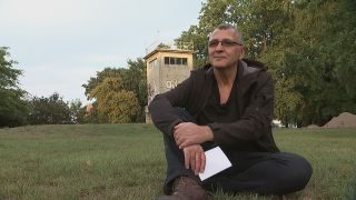 Gastarbeiter Ohran Yüksel sitzt auf der Wiese vor einem ehemaligen Wachturm. (Quelle: rbb/E. Landschek)