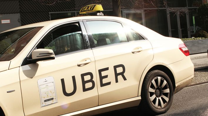 Ein Taxi mit der Werbung für den Fahrdienst Uber steht in Berlin im Bezirk Mitte.