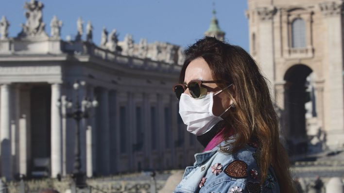 Symbolbild: Eine junge Touristin mit Mundschutz auf Sightseeing Tour. (Quelle: imago images/E. Inetti)