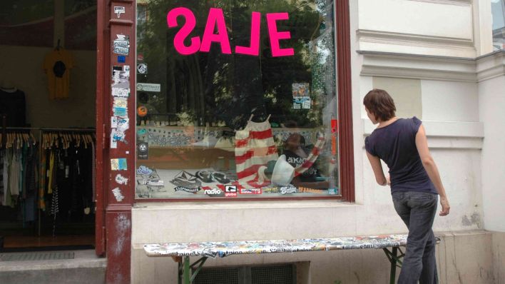 Symbolbild: Eine Frau schaut in einen Laden der einen Ausverkauf anbietet. (Quelle: imago images)