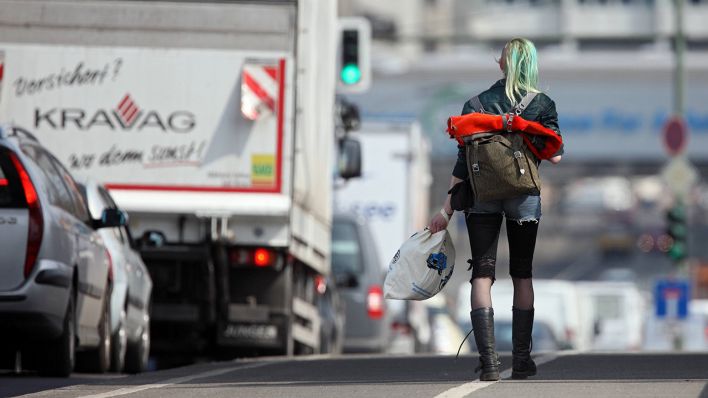 Eine junge Frau mit Rucksack und Tüte läuft in Berlin die Straße entlang. (Quelle: imago-images/Frank Sorge)