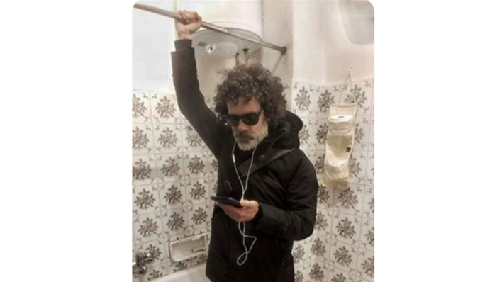 Ein Mann in Winterbekleidung hält sich an der Stange für den Duschvorhang fest und schaut in sein Smartphone (Quelle: Twitter)