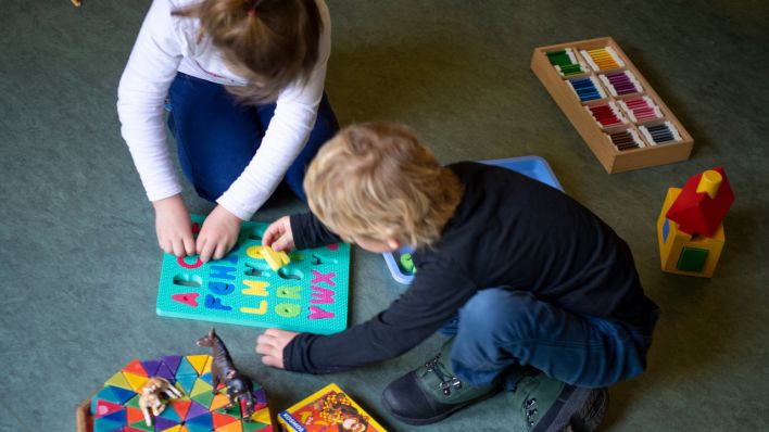Ein Junge und ein Mädchen spielen in einem Kindergarten auf dem Boden. (Quelle: dpa/Monika Skolimowska)