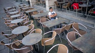 Ein Kellner sitzt am 17.03.2020 mittags in einem Cafe Unter den Linden und wartet vergeblich auf Kundschaft. (Quelle: dpa/Michael Kappeler)