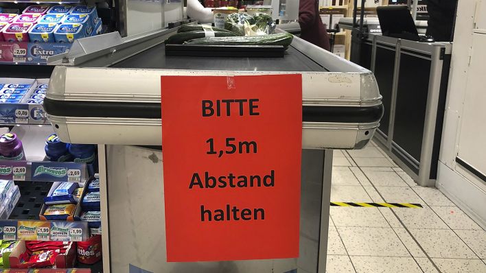Schild " BITTE 1,5 m Abstand halten " ist am 20.03.2020 in einem Supermarkt an der Kasse angebracht. (Quelle: dpa/Sven Simon)