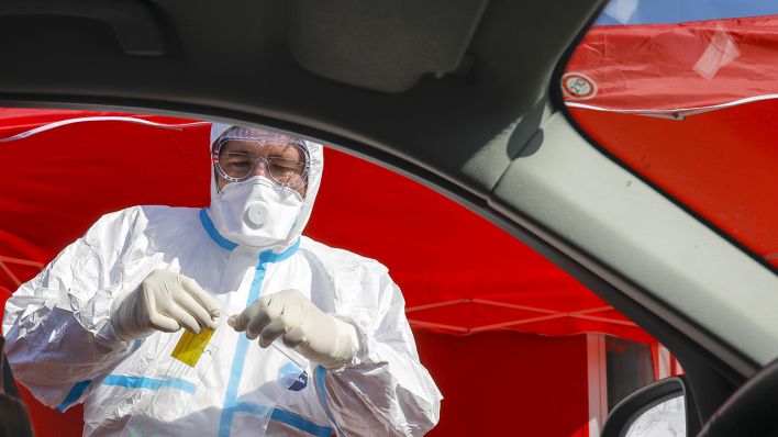 Symbolbild: Mann mit Atemschutzmaske an einem Autofenster. (Quelle: dpa/Rupert Oberhäuser)