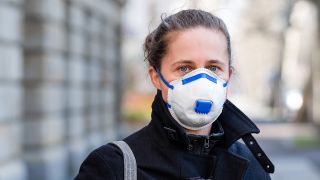 Symbolfoto zum Thema Corona-Pandemie, Covid-19: Eine Frau trägt eine FFP2-Atemschutzmaske und steht auf der Strasse, aufgenommen am 25.03.2020 in Leipzig (Quelle: dpa / Kirsten Nijhof).