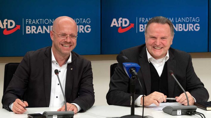 Andreas Kalbitz (l), Vorsitzender und Fraktionsvorsitzender der AfD Brandenburg, und Georg Pazderski, Vorsitzender der AfD-Fraktion im Berliner Abgeordnetenhaus, sitzen nach einer gemeinsamen Sitzung von Berliner und Brandenburger AfD während einer Pressekonferenz lachend nebeneinander. (Quelle: dpa/Soeren Stache)