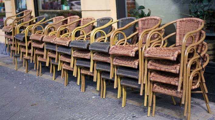 Symbolbild: Aufeinander gestellte Stühle stehen vor einem geschlossenen Café (Quelle: dpa/Reuhl)