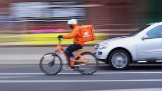 Symbolbild: Ein Fahrer von Lieferando fährt auf seinem Rad in Berlin im Bezirk Kreuzberg auf der Straße. (Quelle: dpa/W. Steinberg)