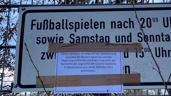 Ein Corona-Hinweis klebt an einem Spielplatzschild in Berlin-Tiergarten