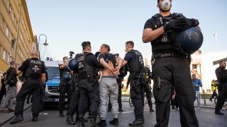 Polizisten mit Atemschutzmasken nehmen am 18.04.2020 einen Demonstranten auf dem Rosa-Luxemburg-Platz fest. Unter den Demonstranten der unerlaubten Demo waren bekannte Verschwörungstheoretiker, Rechtsextreme und Antisemiten (Bild: dpa/Christophe Gateau)