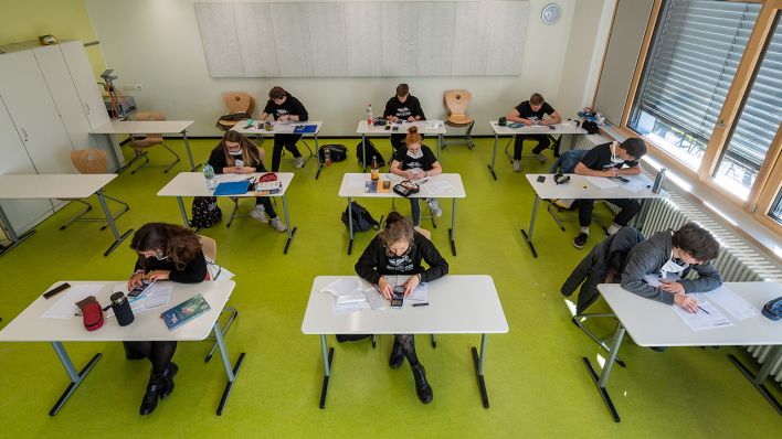 Abiturienten sitzen während der Konsultationen in einem Klassenzimmer, viele mit Maske