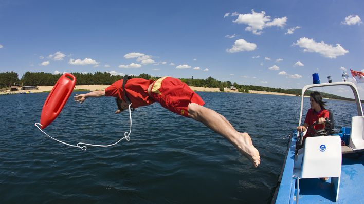 Archiv/Symbol - Der Rettungsschwimmer Christian Budschigk von der Deutschen Lebensrettungsgesellschaft (DLRG) springt während einer Übung in das Wasser (Bild: dpa/Patrick Pleul)