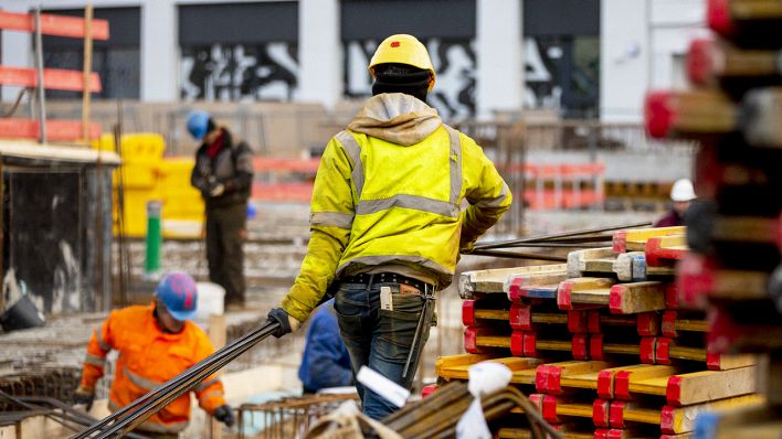 12.02.2020, Berlin: Ein Bauarbeiter trägt auf einer Baustelle nahe des Alexanderplatzes Stahlstangen. (Quelle: dpa/Soeder)