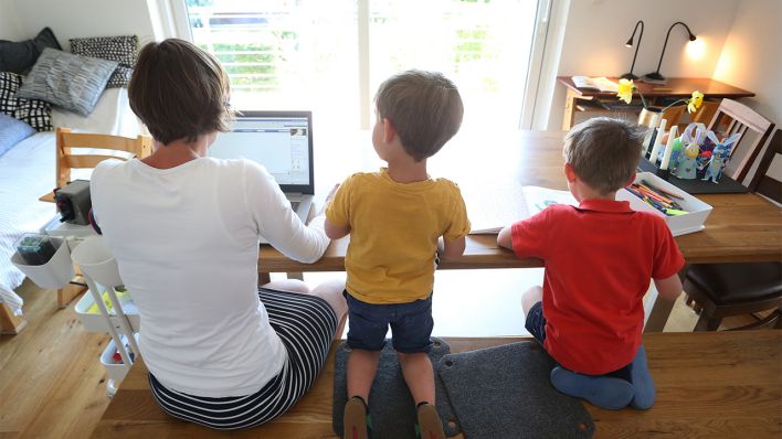 Symbolbild: Eine Frau arbeitet am Computer, während daneben zwei Kinder sitzen. (Quelle: dpa/Karl-Josef Hildenbrand)