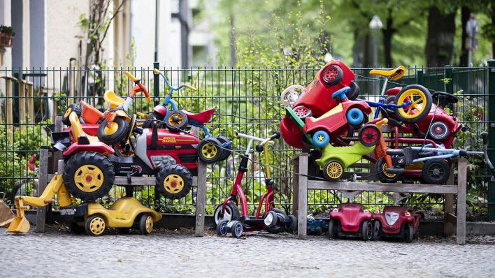 Symbolbild: Bobby-Cars, andere Spielautos und Gefährte für Kinder liegen angeschlossen vor einer Kita in Berlin auf einem Stapel. (Quelle: dpa/Christoph Soeder)