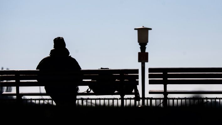 Eine Frau sitzt alleine auf einer Parkbank (Bild: dpa/Julian Stratenschulte)