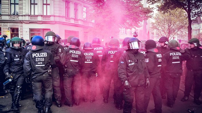 Polizeibeamte einer Hundertschaft stehen während einer Demonstration in Berlin-Kreuzberg im Nebel einer Rauchbombe. (Quelle: dpa/Moll)