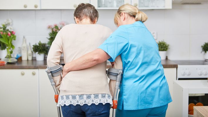 Eine Pflegerin hilft einer älteren Frau (Quelle: dpa/Robert Kneschke)