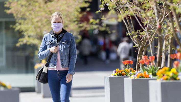 Symbolbild: Eine junge Frau trägt in der Fußgängerzone eine Nase-Mund-Schutzmaske. (Quelle: dpa)