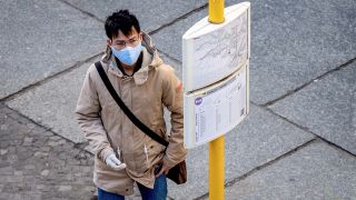 Ein Mann mit Atemschutzmaske und Schutzhandschuhen studiert am 17.04.2020 an einer Bus- und Strassenbahnhaltestelle in Berlin den Fahrplan. (Quelle: dpa/Scheurer)