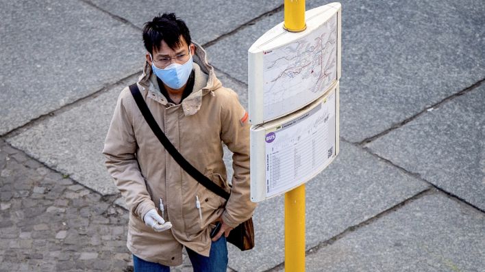 Ein Mann mit Atemschutzmaske und Schutzhandschuhen studiert am 17.04.2020 an einer Bus- und Strassenbahnhaltestelle in Berlin den Fahrplan. (Quelle: dpa/Scheurer)