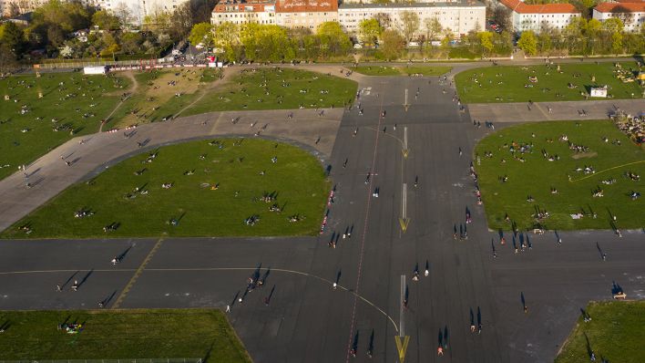 11.04.2020, Berlin: Zahlreiche Menschen sind während des Sonnenuntergangs auf dem Tempelhofer Feld unterwegs - im Hintergrund ist der Bezirk Neukölln zu sehen (Quelle: dpa / Paul Zinken).