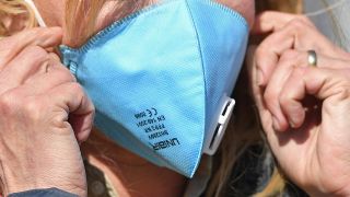 Eine Frau zieht sich eine FFP2 Mundschutzmaske ins Gesicht (Bild: imago images/Frank Hoermann)