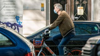 Ein Mann fährt mit Atemschutzmaske und Handschuhen Fahrrad in Berlin (Bild: imago images/T. Seeliger)