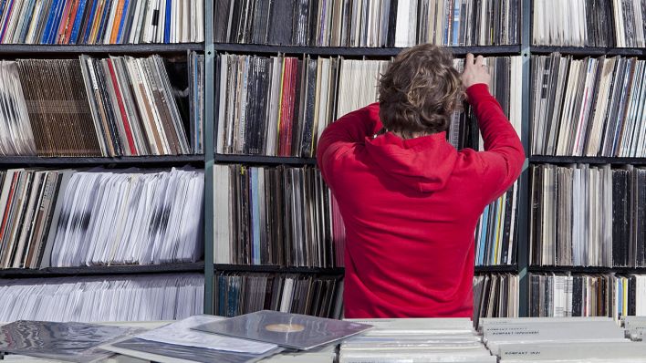 Ein Man holt aus in einem Schallplattenladen eine Schallplatte aus dem Regal (Bild: imago images/Halfdark)