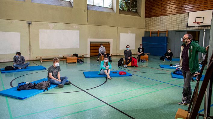 Am 23.04.2020 sitzen Schüler und Schülerinnen auf Matten in einer Turnhalle (Bild: imago images/Christoph Reichwein)
