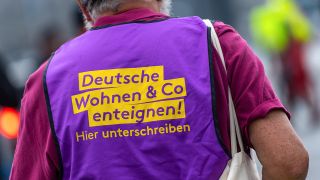 Ein Teilnehmer der Demonstration am 01.05.2019 trägt eine Weste mit der Aufschrift «Deutsche Wohnen Co enteignen!» (Bild: dpa/Monika Skolimowska)
