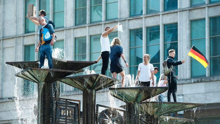 09.05.2020, Berlin: Menschen sind bei einer Demonstration auf dem Alexanderplatz auf den Springbrunnen "Brunnen der Völkerfreundschaft" geklettert. (Quelle: dpa/Christophe Gateau)
