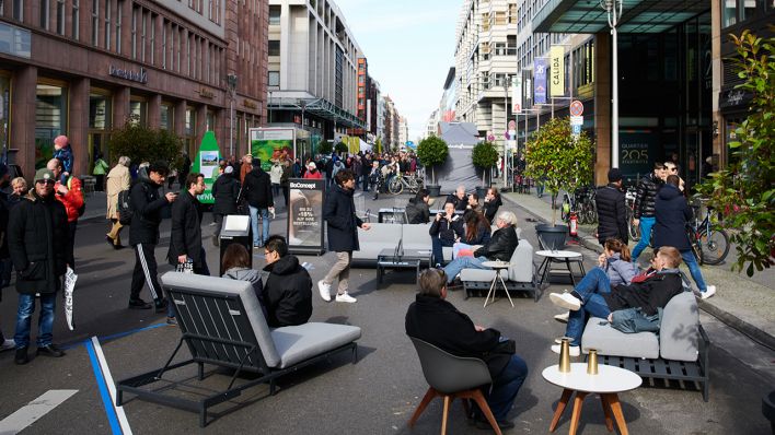 Archivbild: Menschen genießen auf Sitzmöbeln mitten auf der Friedrichstraße die Abwesenheit der Autos. (Quelle: dpa/Annette Riedl)