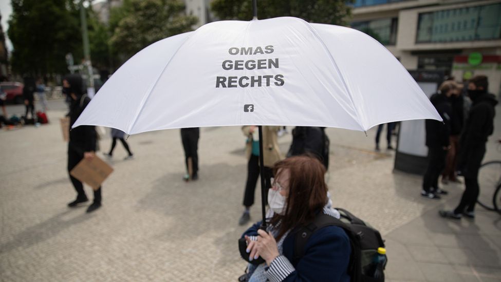 Eine Frau hält bei einer Kundgebung vor dem Mauerpark einen Schirm mit der Aufschrift <<Omas gegen rechts>>. (Quelle: dpa/C. Soeder)